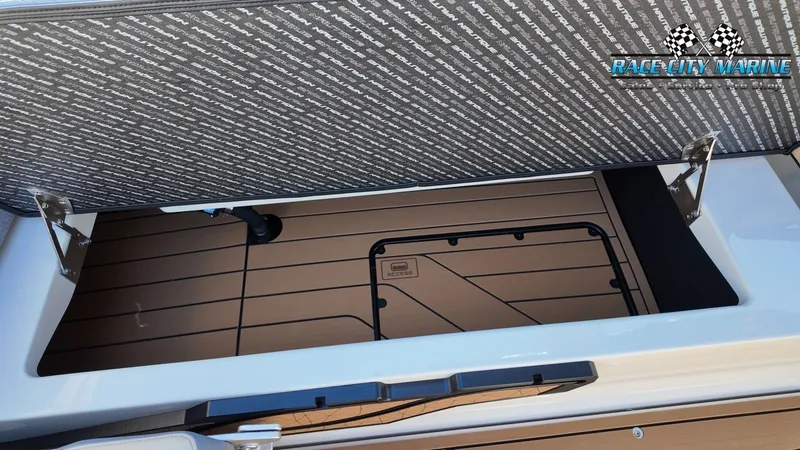 Slide: The Image of An open storage compartment on a 2027 Nautique G25 boat with wood-patterned flooring. - 36