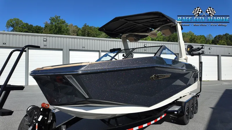 Slide: The Image of A modern Nautique G25 boat from 2027 on a trailer in front of a storage facility. - 6