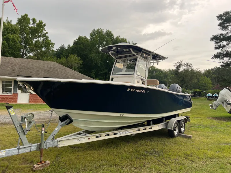 The Image of A 2018 Sportsman Open 252 Center Console boat on a trailer, parked on grass. - 0