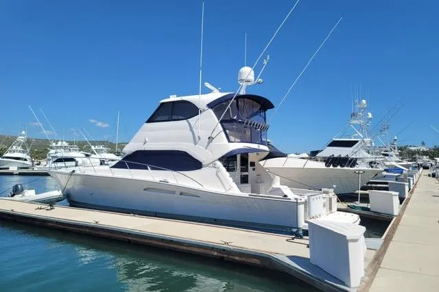 Slide: The Image of 2007 Riviera 51 Enclosed Flybridge yacht docked at marina under clear blue sky. - 5