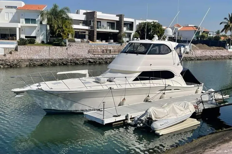 The Image of 2007 Riviera 51 Enclosed Flybridge yacht docked by waterfront homes. - 1