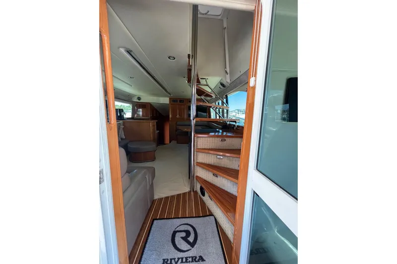 Slide: The Image of Interior view of 2007 Riviera 51 Enclosed Flybridge yacht, featuring elegant wooden stairs and seating. - 9