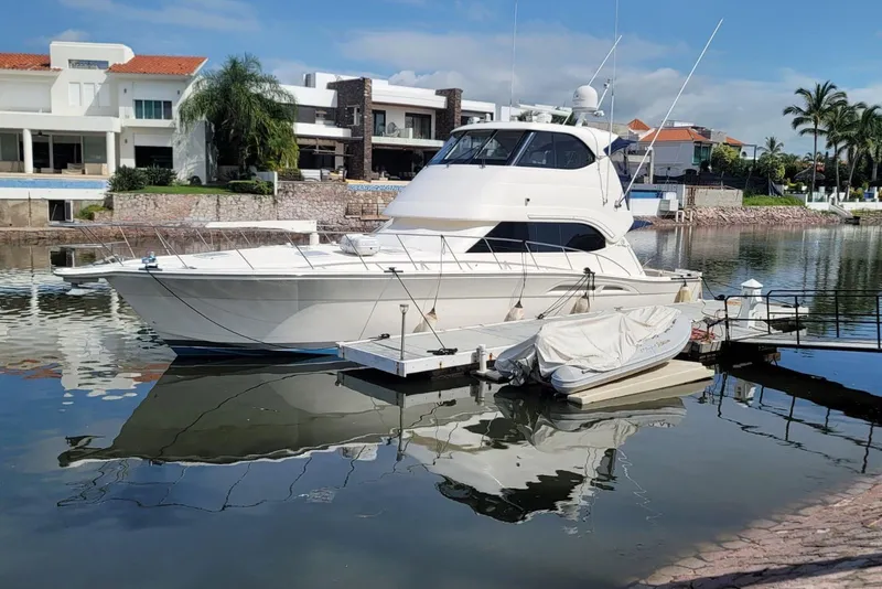 Slide: The Image of 2007 Riviera 51 Enclosed Flybridge yacht docked in a serene waterfront setting. - 3