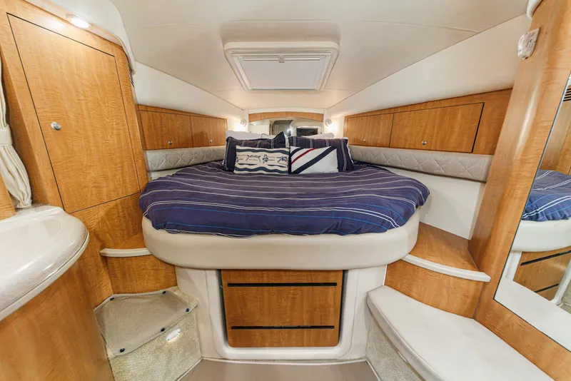Slide: The Image of The cabin of the 2006 Sea Ray 340 Sundancer features a cozy bed with blue bedding. - 23