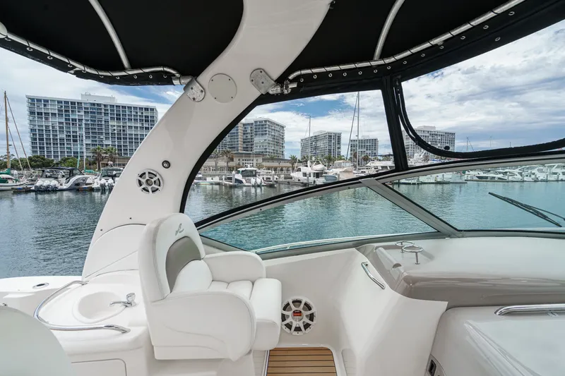 Slide: The Image of The cockpit of a 2006 Sea Ray 340 Sundancer with white seating, overlooking a marina. - 19