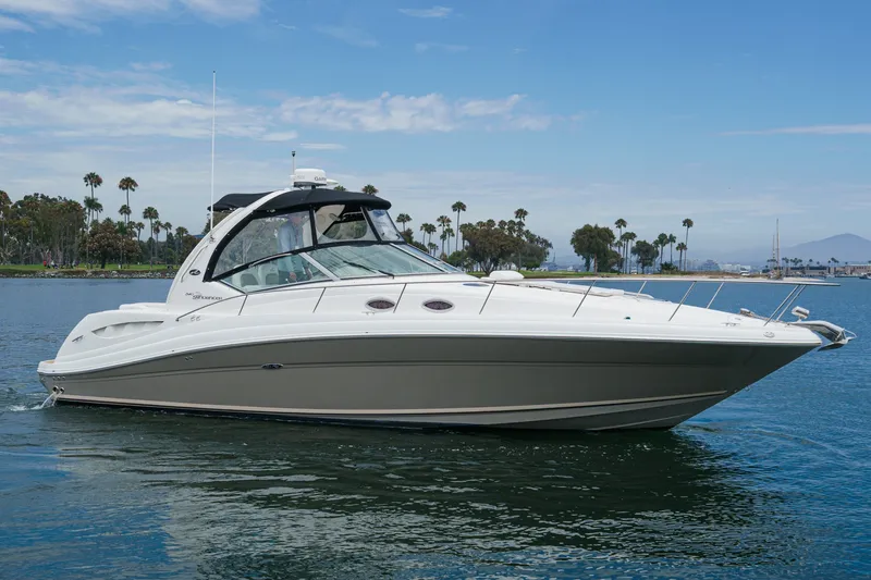 Slide: The Image of The 2006 Sea Ray 340 Sundancer glides on calm water, surrounded by palm trees and blue sky. - 2