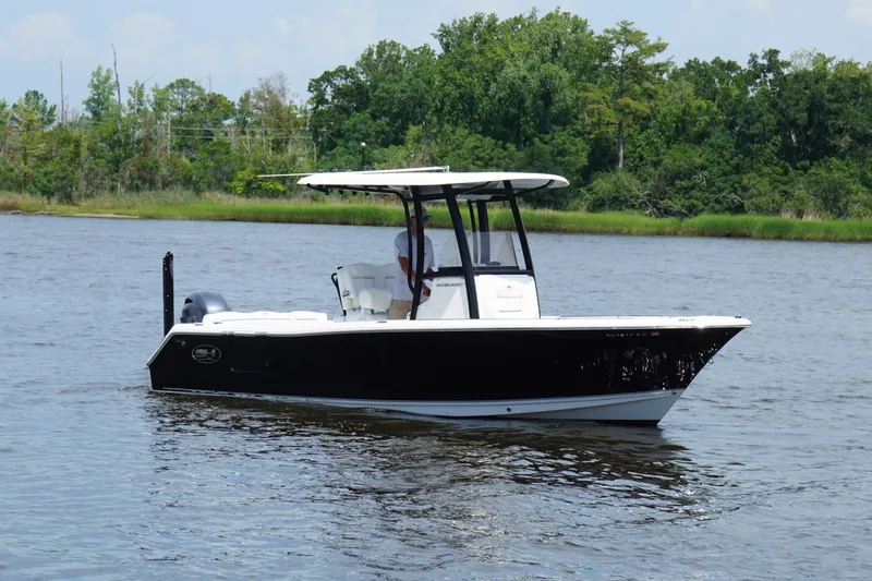 The Image of 2015 Sea Hunt Ultra 235 SE boat on calm water with lush green shoreline. - 0