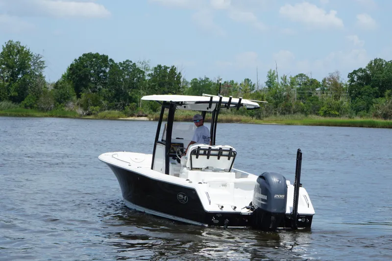 Slide: The Image of 2015 Sea Hunt Ultra 235 SE boat cruising on a calm river with lush greenery. - 18