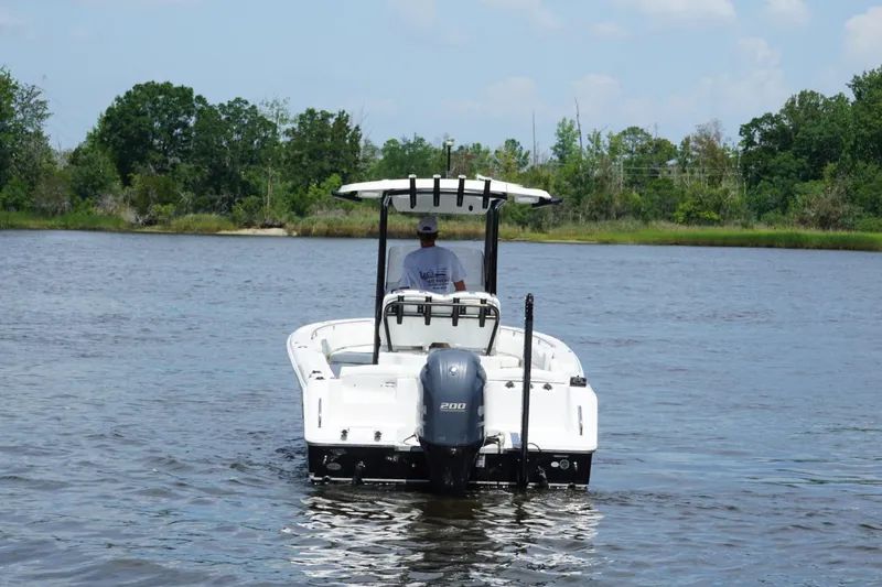Slide: The Image of 2015 Sea Hunt Ultra 235 SE boat on calm water, surrounded by lush greenery. - 3