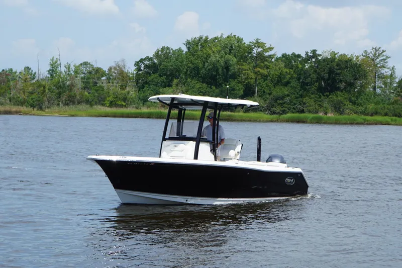 Slide: The Image of 2015 Sea Hunt Ultra 235 SE boat cruising on a calm river with lush green shoreline. - 15
