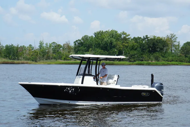Slide: The Image of 2015 Sea Hunt Ultra 235 SE boat cruising on a calm river with lush green background. - 2
