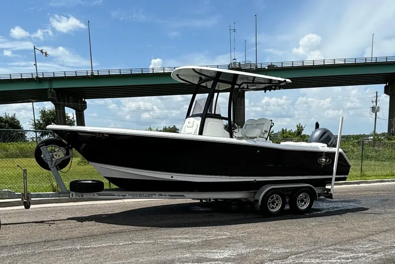 Slide: The Image of 2015 Sea Hunt Ultra 235 SE boat on trailer under a bridge, clear sky background. - 4
