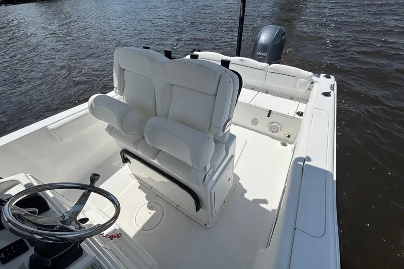 Slide: The Image of 2015 Sea Hunt Ultra 235 SE boat interior with white seating and steering wheel on water. - 22