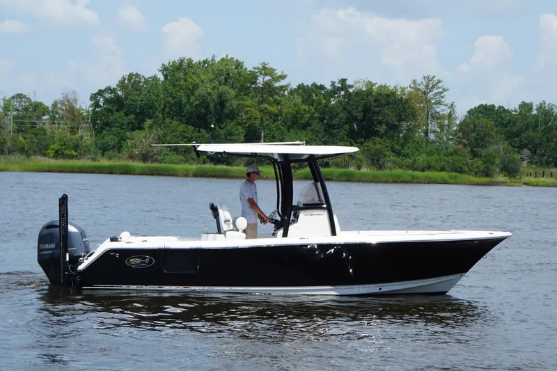 Slide: The Image of 2015 Sea Hunt Ultra 235 SE boat cruising on a calm river with lush greenery. - 16