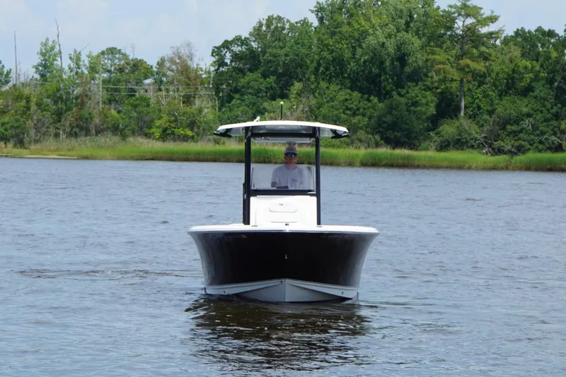 Slide: The Image of 2015 Sea Hunt Ultra 235 SE boat cruising on a calm river with lush greenery. - 1