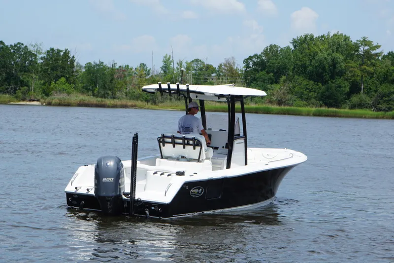 Slide: The Image of 2015 Sea Hunt Ultra 235 SE boat cruising on a calm river with lush greenery. - 17