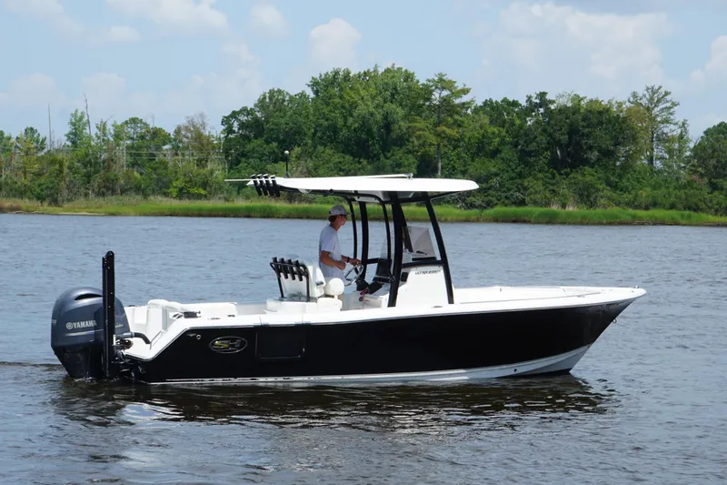 Slide: The Image of 2015 Sea Hunt Ultra 235 SE boat cruising on a calm river with lush greenery. - 19