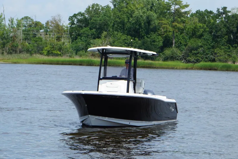 Slide: The Image of 2015 Sea Hunt Ultra 235 SE boat cruising on a calm river with lush greenery. - 25