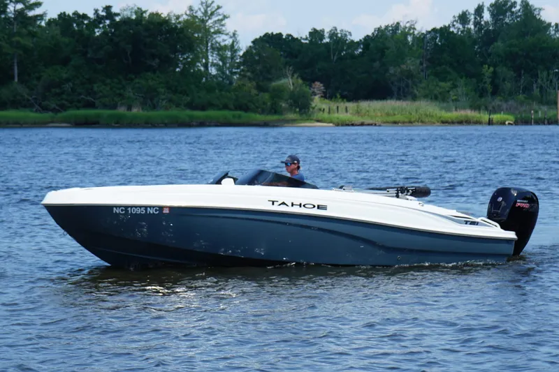 The Image of 2024 Tahoe T21 boat cruising on a serene lake with lush greenery in the background. - 0