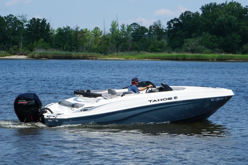 Slide: The Image of 2024 Tahoe T21 boat cruising on a serene lake with lush greenery in the background. - 5