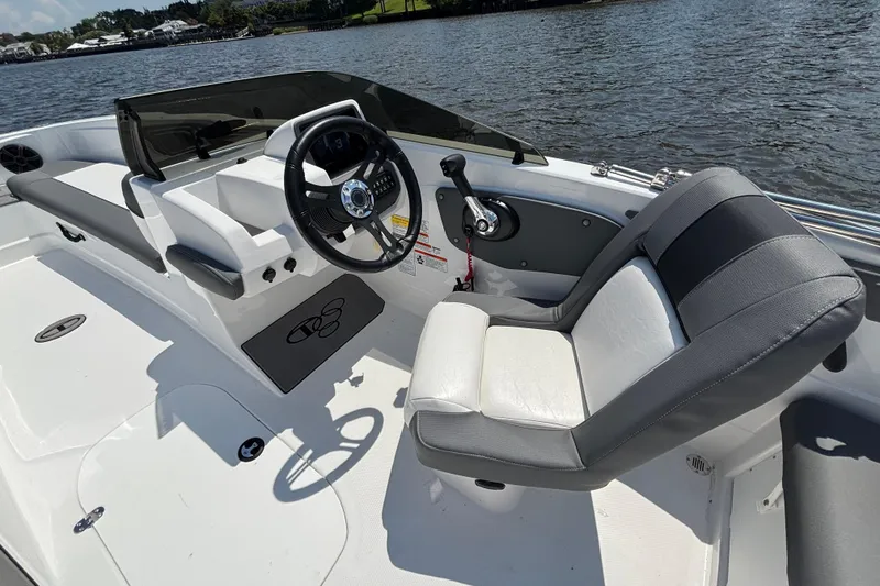 Slide: The Image of 2024 Tahoe T21 boat interior with steering wheel and seating, on a calm lake. - 11