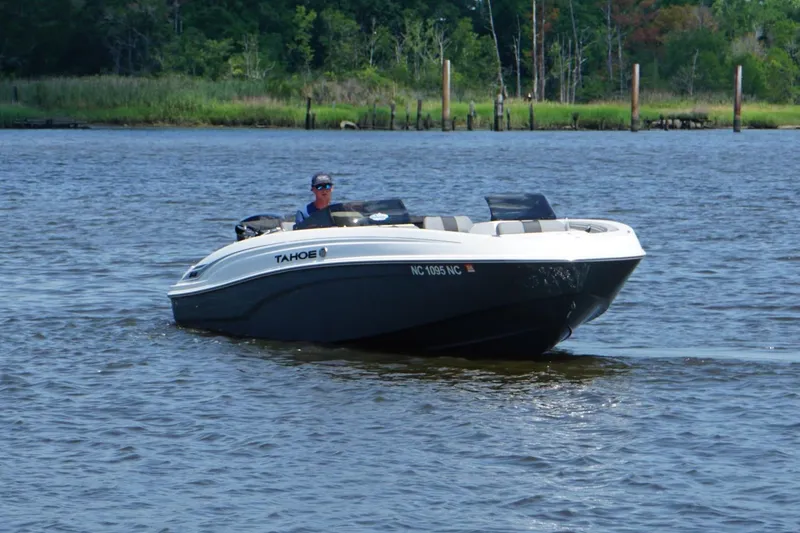 Slide: The Image of 2024 Tahoe T21 boat cruising on a calm river with lush greenery in the background. - 2
