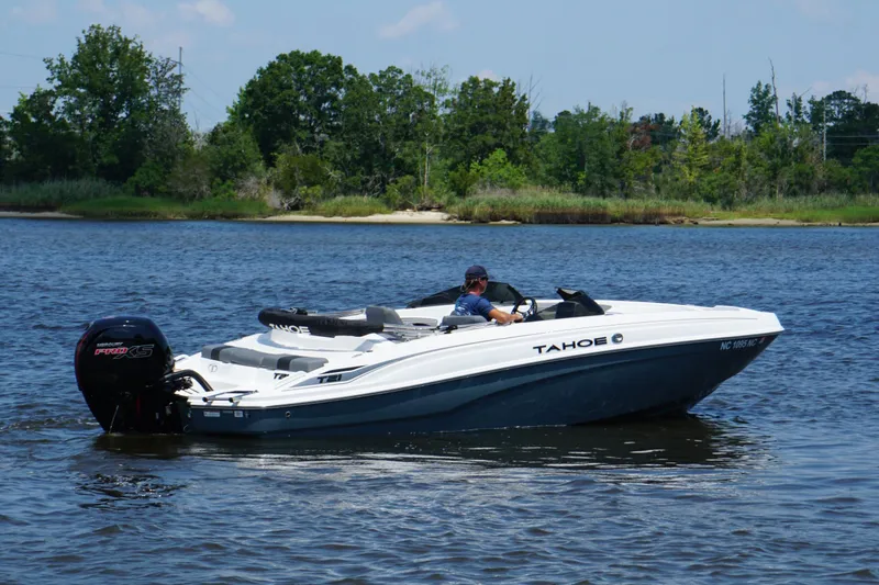 Slide: The Image of 2024 Tahoe T21 boat cruising on a serene lake with lush greenery in the background. - 22