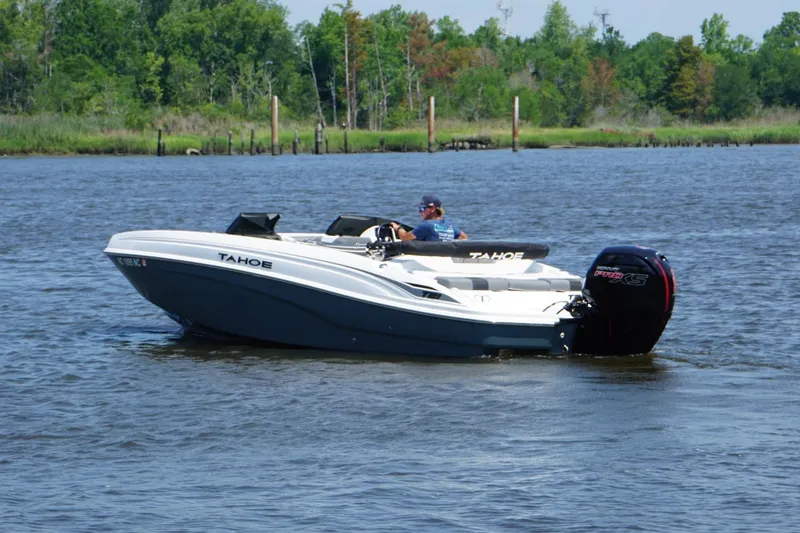 Slide: The Image of 2024 Tahoe T21 boat cruising on a calm river with lush green trees. - 21