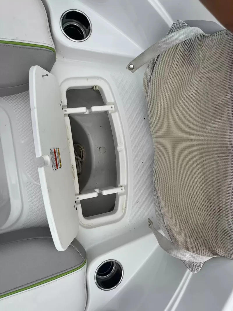 Slide: The Image of An open storage compartment on a boat with gray upholstery and cup holders. - 18