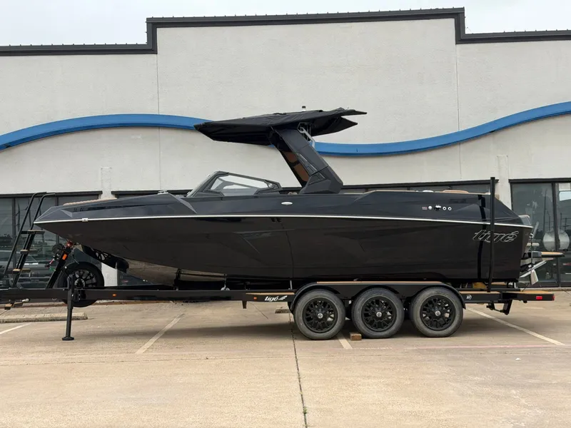 The Image of A black 2027 Tigé 24RZX boat on a trailer in front of a building. - 1
