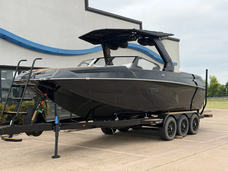 Slide: The Image of A black 2027 Tigé 24RZX boat on a trailer in front of a building. - 2
