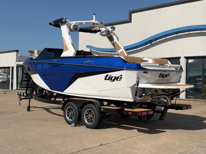 Slide: The Image of A blue and white 2027 Tigé Z1 boat on a trailer in front of a building. - 3
