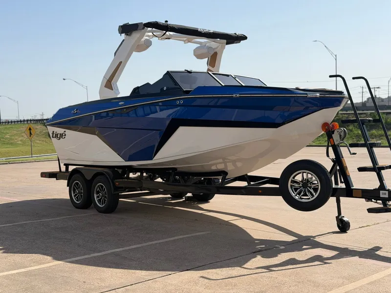 Slide: The Image of A blue and white 2027 Tigé Z1 boat on a trailer in a parking lot. - 6