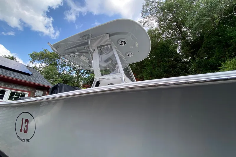 Slide: The Image of 2018 Sportsman Open 242 Center Console boat with T-top, docked near trees and building. - 2