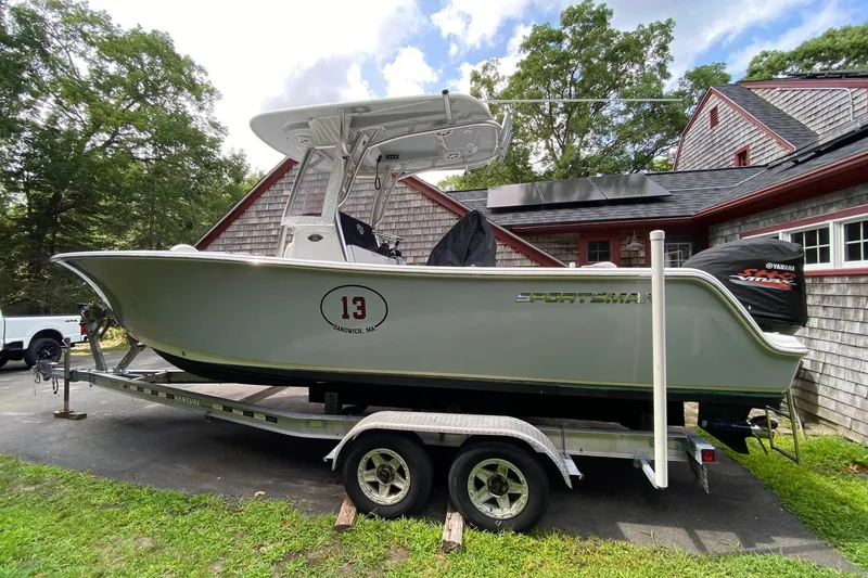 Slide: The Image of 2018 Sportsman Open 242 Center Console boat on trailer, parked near a house. - 21