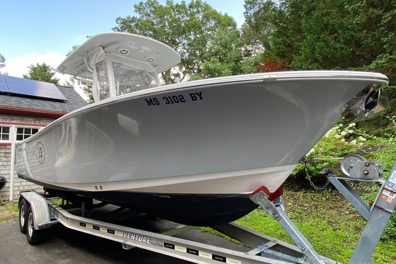 Slide: The Image of 2018 Sportsman Open 242 Center Console boat on trailer, parked near a house with solar panels. - 28