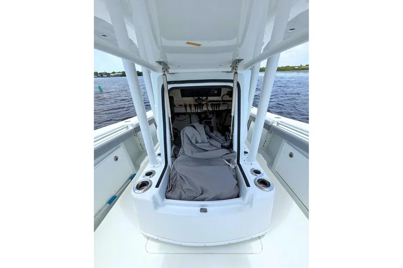 Slide: The Image of 2018 Yellowfin 26 Hybrid boat interior with storage compartment and cup holders on a calm water backdrop. - 16