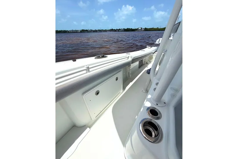 Slide: The Image of 2018 Yellowfin 26 Hybrid boat interior with rod holders, on calm water under blue skies. - 15