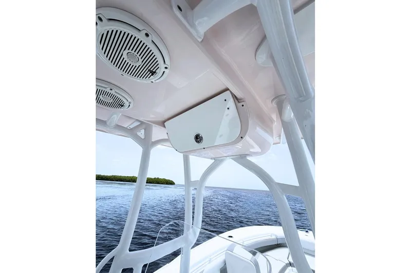 Slide: The Image of 2018 Yellowfin 26 Hybrid boat interior with speakers and storage, overlooking calm waters. - 17