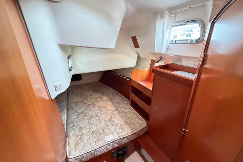 Slide: The Image of 2007 Beneteau 423 yacht cabin interior with bed, wooden cabinetry, and porthole window. - 39