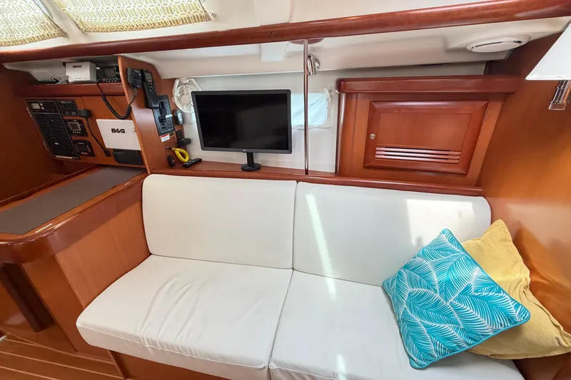 Slide: The Image of Interior of 2007 Beneteau 423 yacht with white seating, colorful pillows, and navigation equipment. - 37