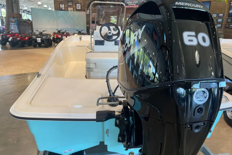 Slide: The Image of 2026 Mako Pro Skiff 15 CC with Mercury 60 engine displayed indoors. - 3