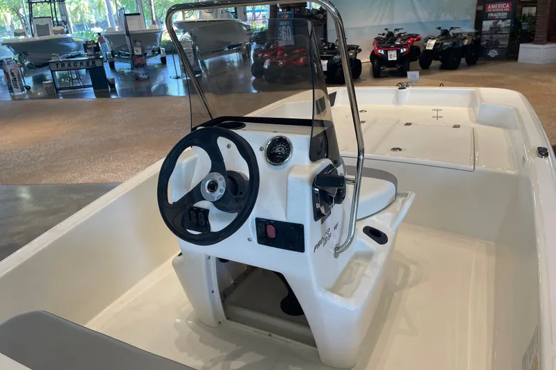 Slide: The Image of 2026 Mako Pro Skiff 15 CC boat interior with steering console in showroom. - 2