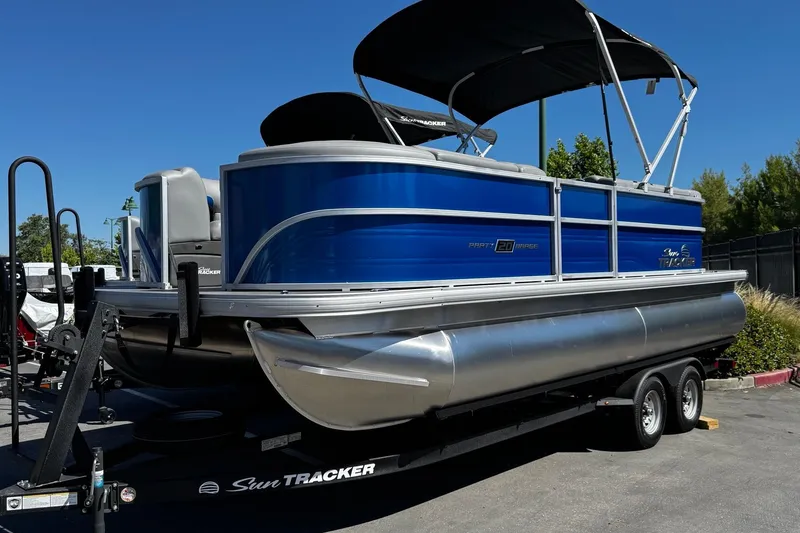 Slide: The Image of 2026 Sun Tracker Party Barge 20 DLX pontoon boat on trailer, blue and silver design. - 2