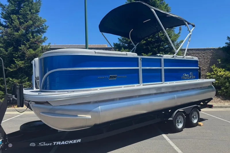 Slide: The Image of 2026 Sun Tracker Party Barge 20 DLX pontoon boat on trailer, blue and silver design. - 4