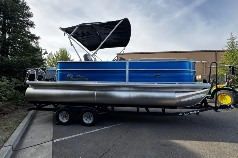 Slide: The Image of 2026 Sun Tracker Party Barge 20 DLX pontoon boat on trailer, parked outdoors. - 5