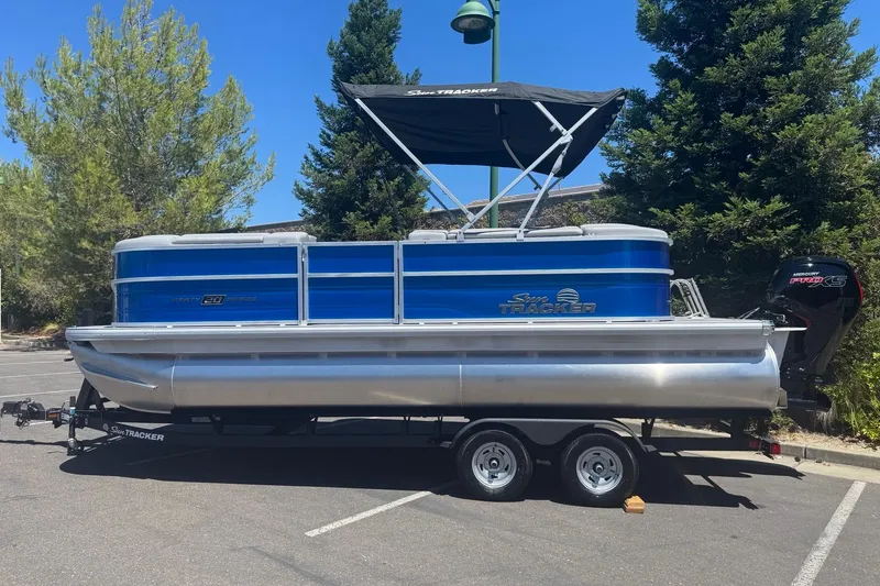 Slide: The Image of 2026 Sun Tracker Party Barge 20 DLX pontoon boat on trailer, parked outdoors. - 10