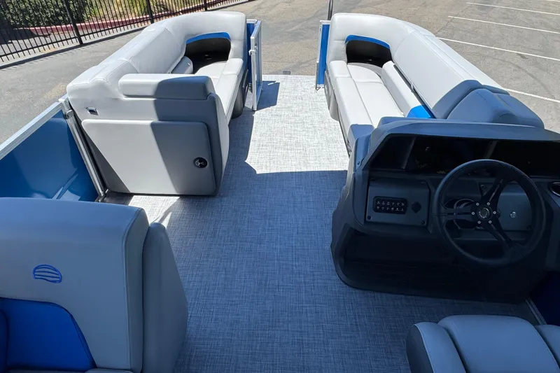Slide: The Image of 2026 Sun Tracker Party Barge 20 DLX interior with gray seating and steering console. - 18