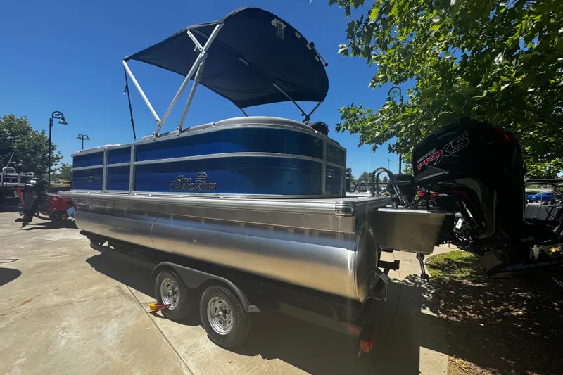 Slide: The Image of 2026 Sun Tracker Party Barge 20 DLX pontoon boat with canopy and trailer in sunny setting. - 8