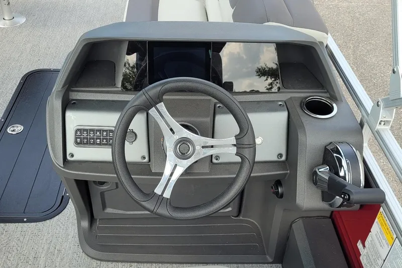 Slide: The Image of Steering console of 2026 Sun Tracker Fishin' Barge 22 XP3 with modern controls and cup holder. - 4